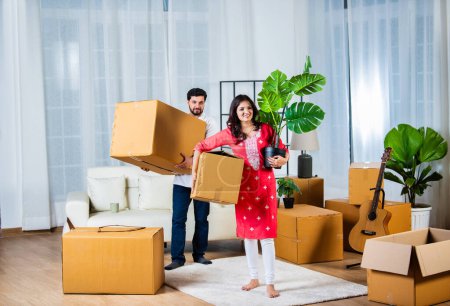 Photo for Indian young couple shifting home holding boxes in new home - Royalty Free Image