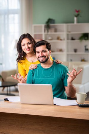 Foto de Feliz joven pareja casada india sentarse en la mesa calcular los gastos utilizar fácil servicio de banca en línea en casa - Imagen libre de derechos