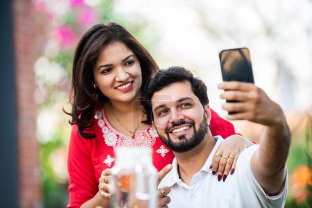 Photo for Young Indian couple using smart phone and tablet pc in the outdoor cafe - Royalty Free Image