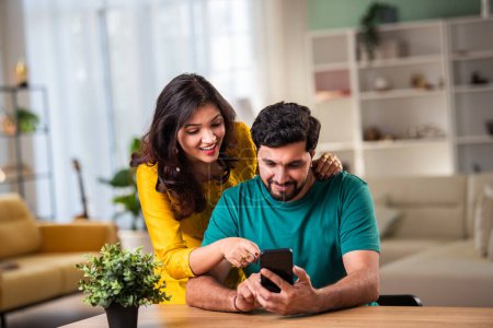 Photo for Indian young couple using smartphone at home - Royalty Free Image