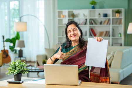 Photo for Senior Indian asian woman using laptop and papers for accounting at home - Royalty Free Image