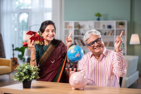 Foto de Indio jubilado jubilado pareja planificación vacaciones con ordenador portátil, avión de juguete, globo modelo - Imagen libre de derechos