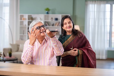 Indian retired senior couple using smartphone at home