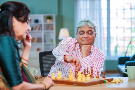 Téléchargez les photos : Senior indien asiatique couple jouer aux échecs ensemble à la maison sur la table - en image libre de droit