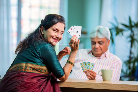 Téléchargez les photos : Senior indien asiatique couple appréciant jouer cartes ensemble à la maison - en image libre de droit