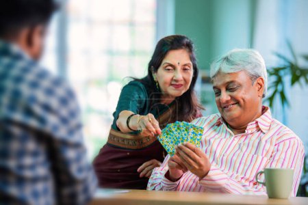 Téléchargez les photos : Senior indien asiatique couple appréciant jouer cartes ensemble à la maison - en image libre de droit