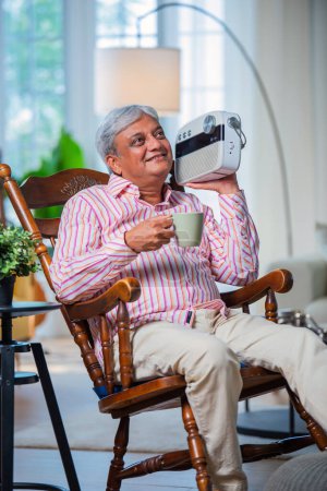 Téléchargez les photos : Retraité asiatique indien homme écouter de vieilles chansons sur vintage radio à la maison - en image libre de droit