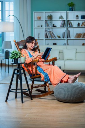 Foto de Anciano indio mujer asiática usando tableta digital o computadora portátil en casa. Concepto de tecnología y personas mayores. - Imagen libre de derechos
