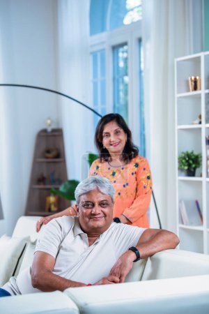 Elderly Indian asian couple sitting on sofa or couch in living room