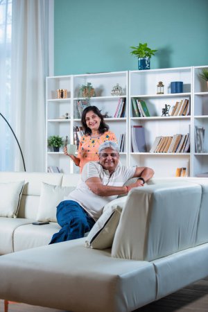Elderly Indian asian couple sitting on sofa or couch in living room