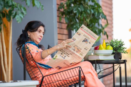 Photo for Indian asian elderly woman reads newspaper in the morning in home gallery - Royalty Free Image