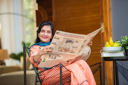 Foto de Indio asiático anciano mujer lee periódico en la mañana en casa galería - Imagen libre de derechos
