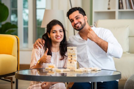 Foto de India joven casado pareja jugando jenga mesa juego en casa divertirse - Imagen libre de derechos