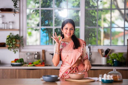 Photo for Attractive Indian asian young female in saree working in kitchen - Royalty Free Image