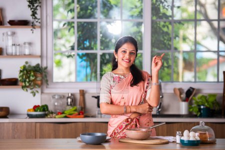 Photo for Attractive Indian asian young female in saree working in kitchen - Royalty Free Image