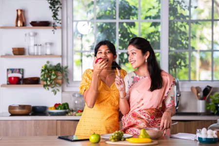 Téléchargez les photos : Ludique petit indien asiatique fille cuisine avec son mère - en image libre de droit