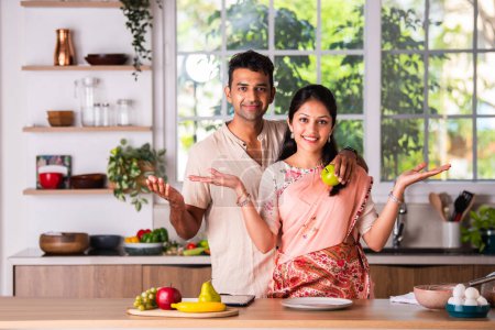 Téléchargez les photos : Indien asiatique jeune couple cuisine dans la cuisine, garniture sur plaque vide - en image libre de droit