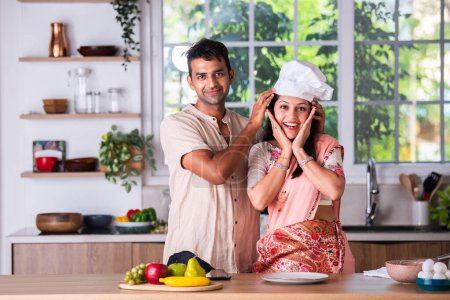 Photo for Indian asian young couple cooking in the kitchen, garnishing on empty plate - Royalty Free Image