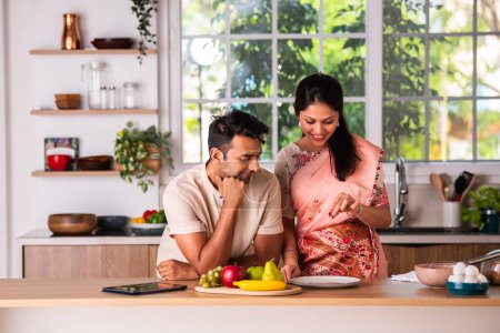 Photo for Indian asian young couple cooking in the kitchen, garnishing on empty plate - Royalty Free Image