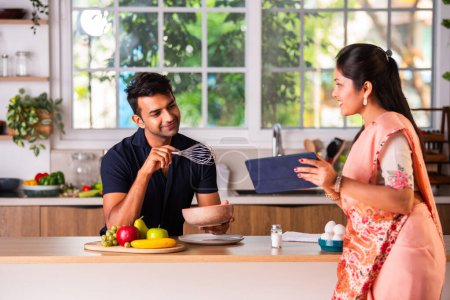 Photo for Indian asian young couple working in kitchen preparing meal - Royalty Free Image