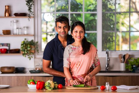Photo for Indian asian young couple working in kitchen preparing meal - Royalty Free Image