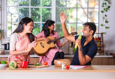 Téléchargez les photos : Famille indienne chantant à la guitare dans la cuisine - en image libre de droit