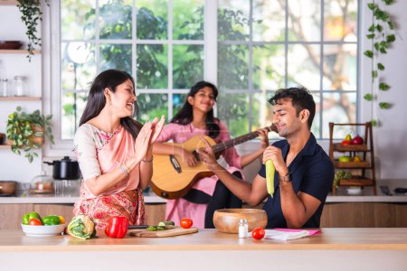 Photo for Indian family singing playing guitar in the kitchen - Royalty Free Image