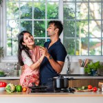 Cheerful millennial Indian asian husband and wife having fun and dancing in modern kitchen interior