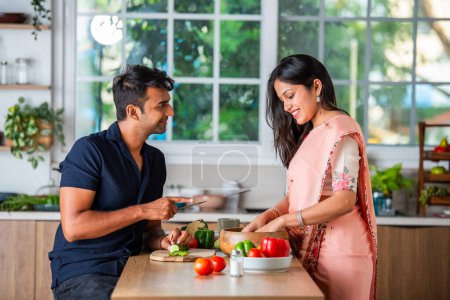 Téléchargez les photos : Heureux couple indien asiatique hacher ou couper des légumes dans la cuisine - en image libre de droit