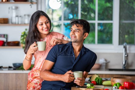 Photo for Indian asian young couple having tea or coffee in the kitchen - Royalty Free Image