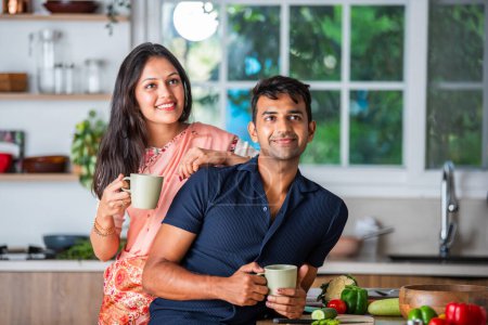Téléchargez les photos : Indien asiatique jeune couple ayant thé ou café dans la cuisine - en image libre de droit