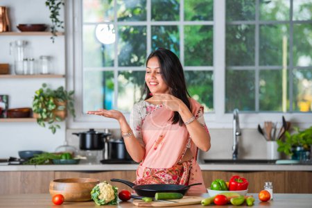 Foto de Indio asiático joven mujer señalando, impactante o promoviendo utensilios, olla, espátula, plato vacío, ok signo - Imagen libre de derechos