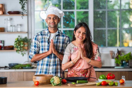 Téléchargez les photos : Indien asiatique marié couple dans cuisine promotion ustensiles, plat vide avec ok signe - en image libre de droit