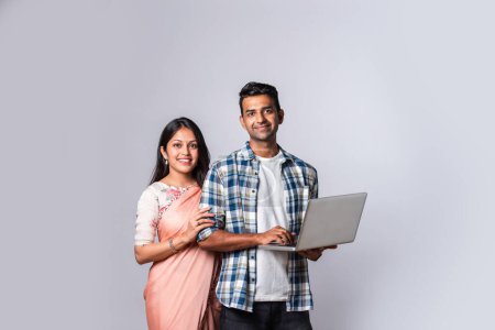 Photo for Indian asian married young couple using laptop while standing isolated on white - Royalty Free Image