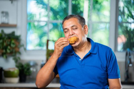 Foto de Asiático indio mediana edad hombre comer frito pollo pierna pedazo - Imagen libre de derechos