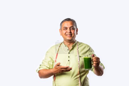 Photo for Indian asian Handsome mid age man man drinking healthy green drink or smoothie in kitchen - Royalty Free Image