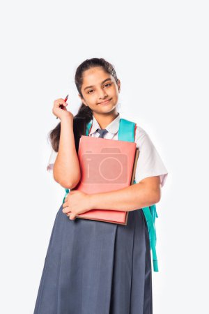 Téléchargez les photos : Indien asiatique écolière dans école uniforme debout avec livres contre blanc - en image libre de droit