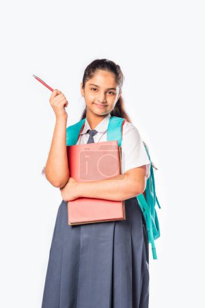 Photo for Indian asian schoolgirl in school uniform standing with books against white - Royalty Free Image