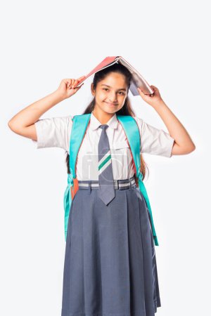 Photo for Indian asian schoolgirl in school uniform standing with books against white - Royalty Free Image