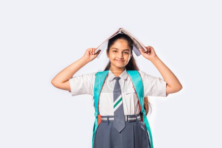Téléchargez les photos : Indien asiatique écolière dans école uniforme debout avec livres contre blanc - en image libre de droit