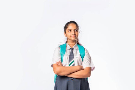 Foto de India asiático expresivo adolescente escuela chica con uniforme y mochila de pie aislado contra blanco - Imagen libre de derechos