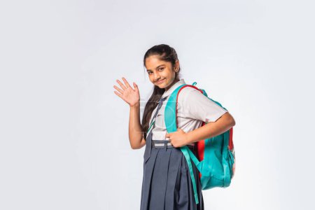 Photo for Indian asian expressive teen school girl with uniform and backpack standing isolated against white - Royalty Free Image