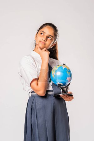 Téléchargez les photos : Indien asiatique adolescent écolière étudiant géographie et tenant globe modèle sur fond blanc - en image libre de droit