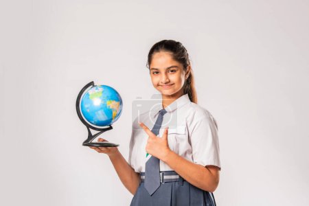 Téléchargez les photos : Indien asiatique adolescent écolière étudiant géographie et tenant globe modèle sur fond blanc - en image libre de droit