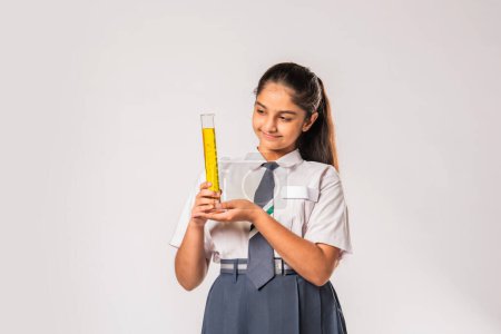 Foto de India asiático colegiala en escuela uniforme haciendo ciencia experimento con químico en frasco - Imagen libre de derechos