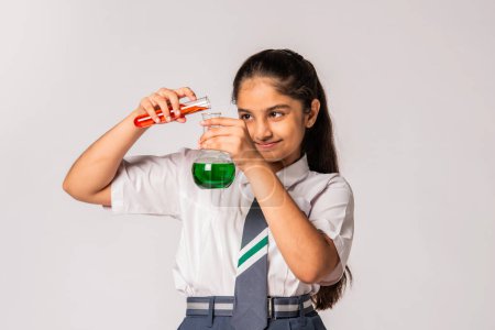 Photo for Indian asian schoolgirl in school uniform doing science experiment with chemical in flask - Royalty Free Image