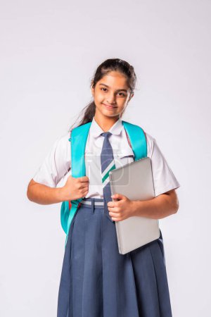 Photo for Indian asian schoolgirl in uniform holding laptop computer against white background - Royalty Free Image