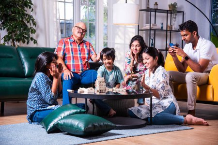 Téléchargez les photos : Indien asiatique multigenerational famille joue en bois bloc empilage jeu à la maison ensemble et avoir amusant - en image libre de droit