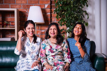 Photo for Portrait of happy Indian asian three generations of females, grandma, daughter and grand daughter sitting on sofa - Royalty Free Image