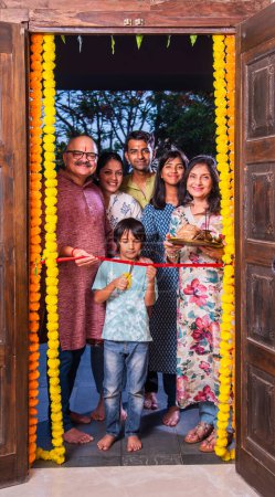 Téléchargez les photos : Famille indienne entrant dans une nouvelle maison appelée gruhapravesh avec puja thali et clés - en image libre de droit